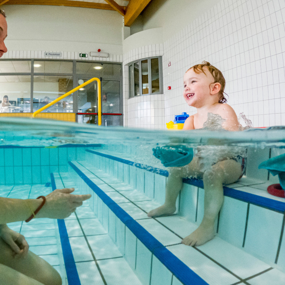 Watergewenning mama en peuter in zwembad