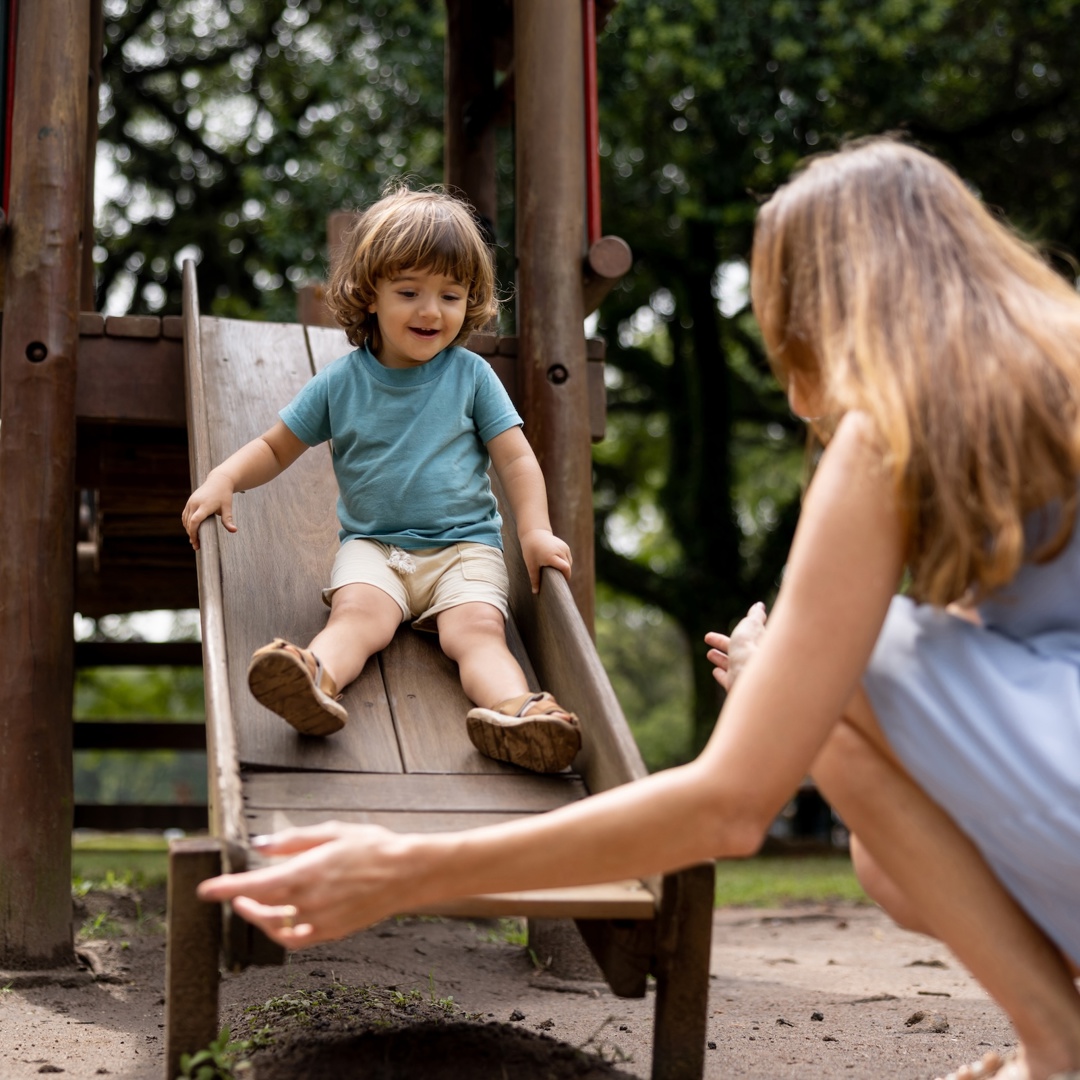 Moeder kijkt naar jong kind op glijbaan: kinderen overbeschermen