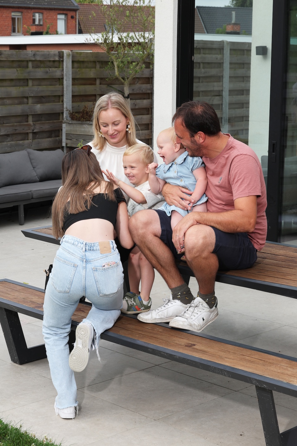 Femke en Hannes zitten buiten op bank met hun kinderen terwijl ze vertellen over evenwicht gezin en werk
