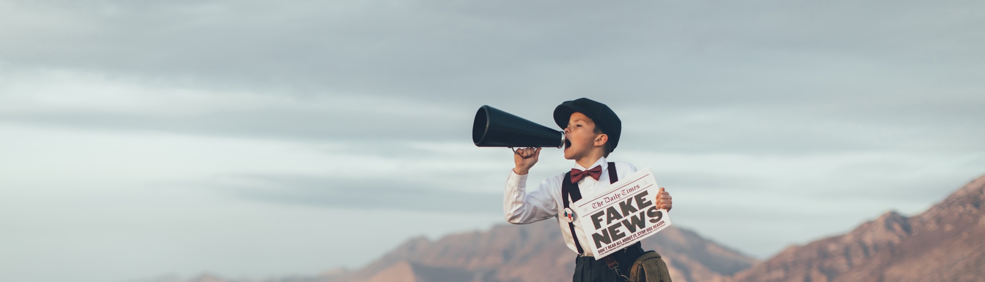 Jongen met megafoon op stoel over Fake News