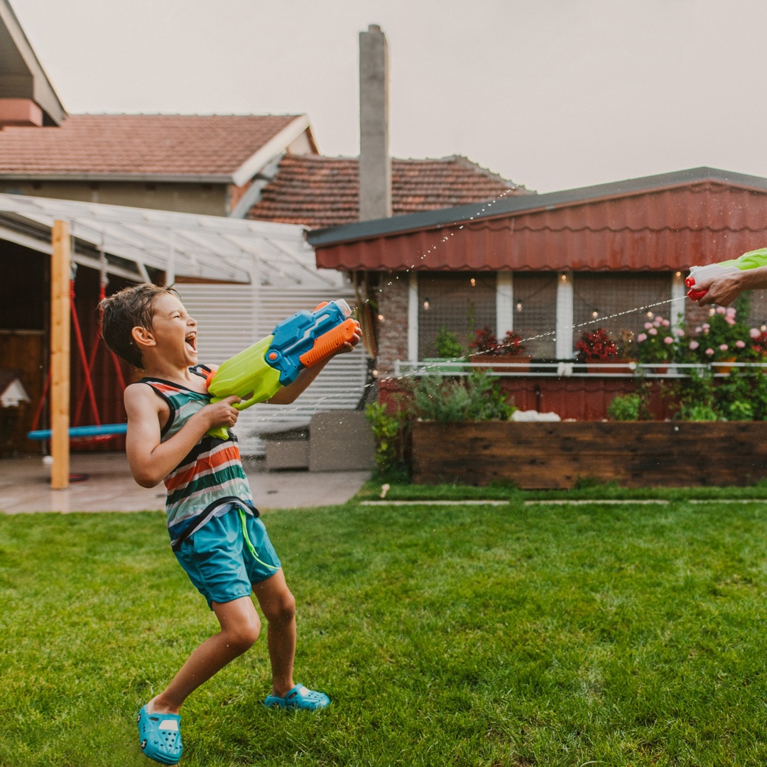 Kind en vader spelen met waterpistool speelgoedgeweer