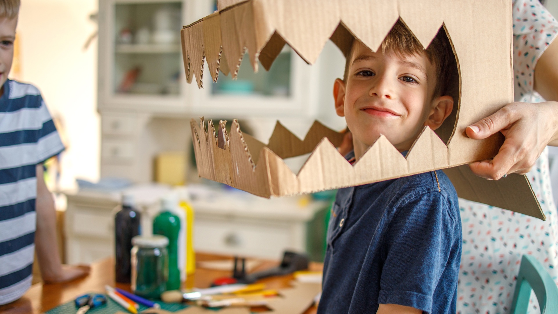 Kind knutselt kartonnen dino voor carnaval op school