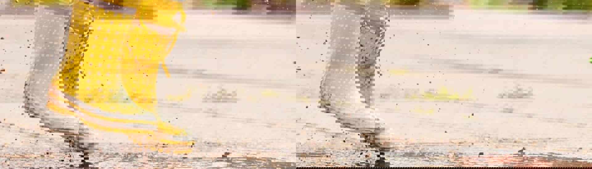 Kind springt met laarzen in een plas