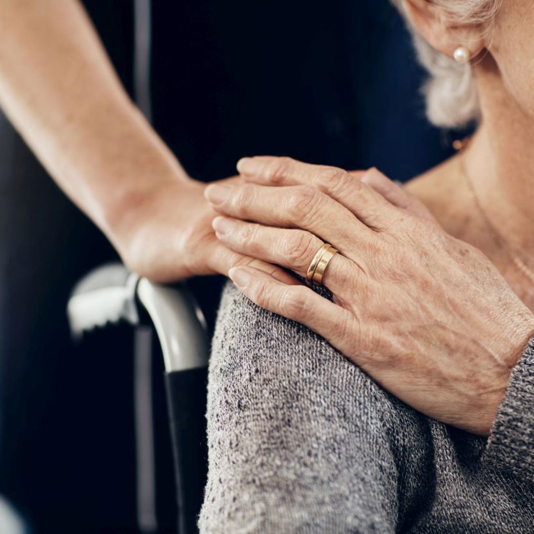 Zorgverlener legt hand op schouder bij oudere vrouw