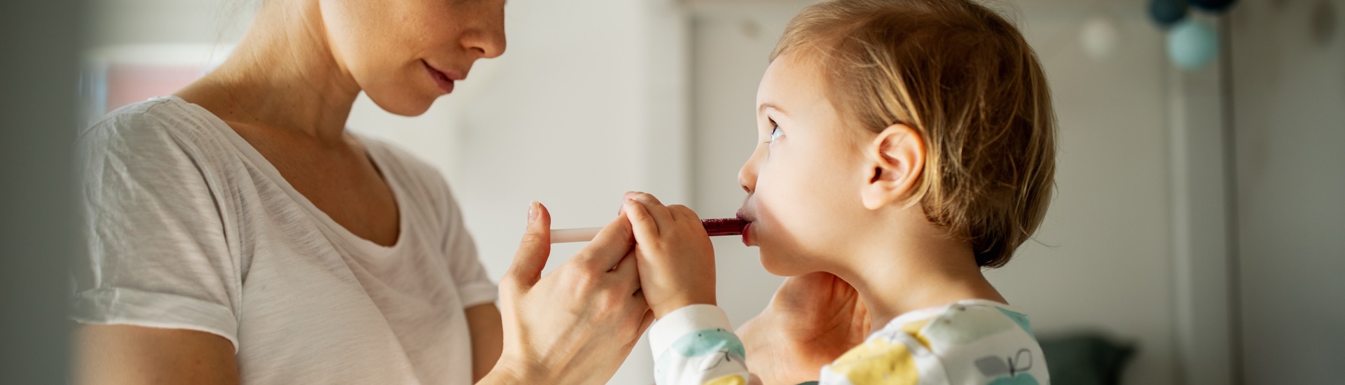 Mama geeft kleuter siroop: kinderen medicijnen innemen 